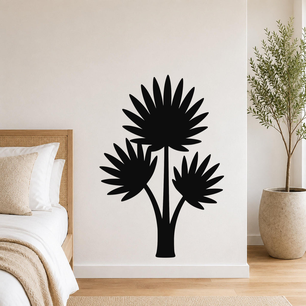 Black metal wall art silhouette of a fan palm tree with three fronds, mounted on a white bedroom wall above a bed.