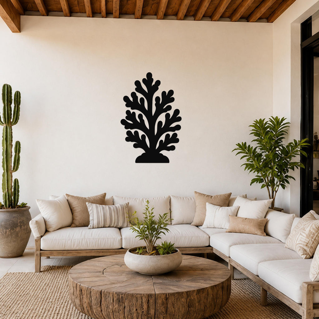 Black metal coral wall art with branching cutouts, mounted on a living room wall above a white sofa.