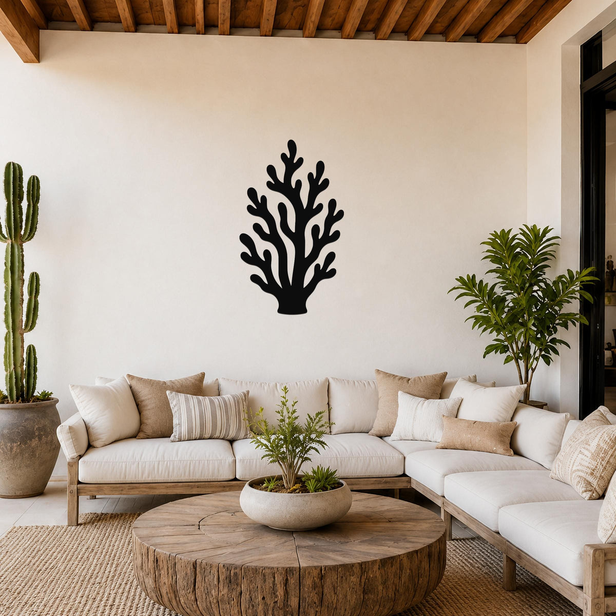 Black metal coral wall art with branching cutouts, mounted on a white wall above a white sofa in a living room.
