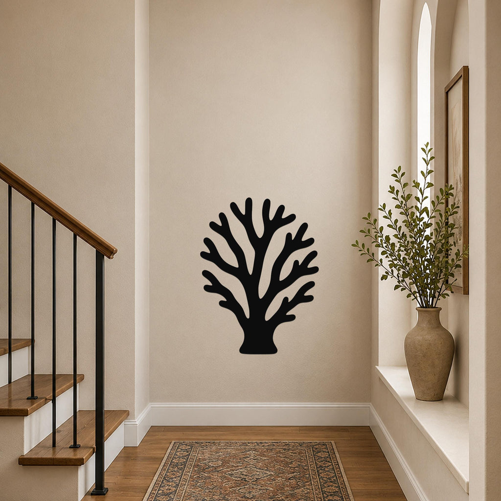 Black metal branching coral wall art with intricate cutout details, mounted on a hallway wall above a patterned rug near a staircase.