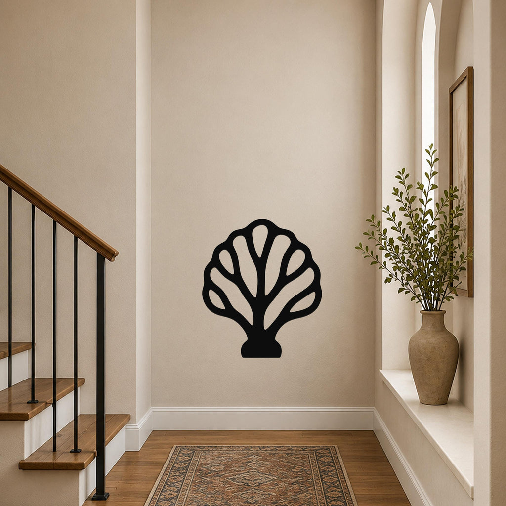 Black metal wall art in a fan coral silhouette with internal cutouts, mounted on a hallway wall above a patterned rug near a staircase.