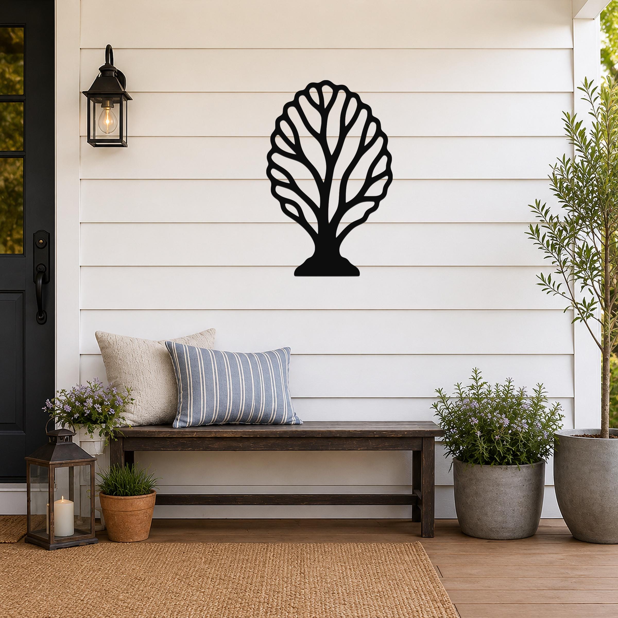 Black metal wall art in a fan coral silhouette, mounted on a white shiplap wall above a wooden bench on a porch.