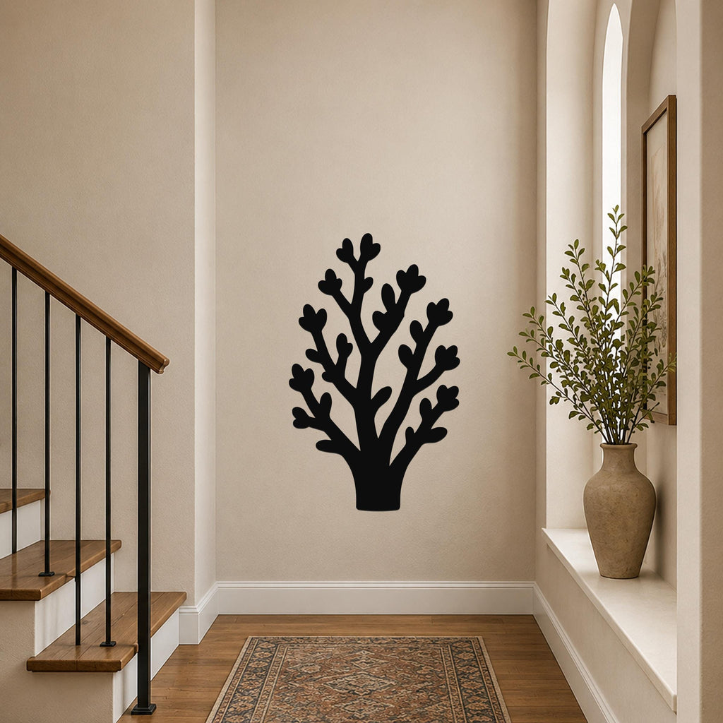 Black metal wall art in a tree silhouette with branching cutouts, mounted on a hallway wall above a patterned rug near a staircase.