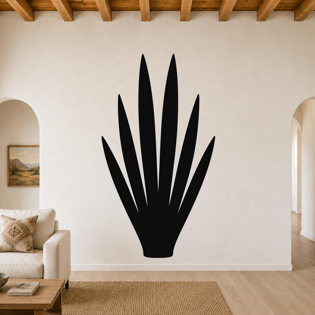 Black metal yucca wall art silhouette with pointed leaves, mounted on a living room wall above a sofa.