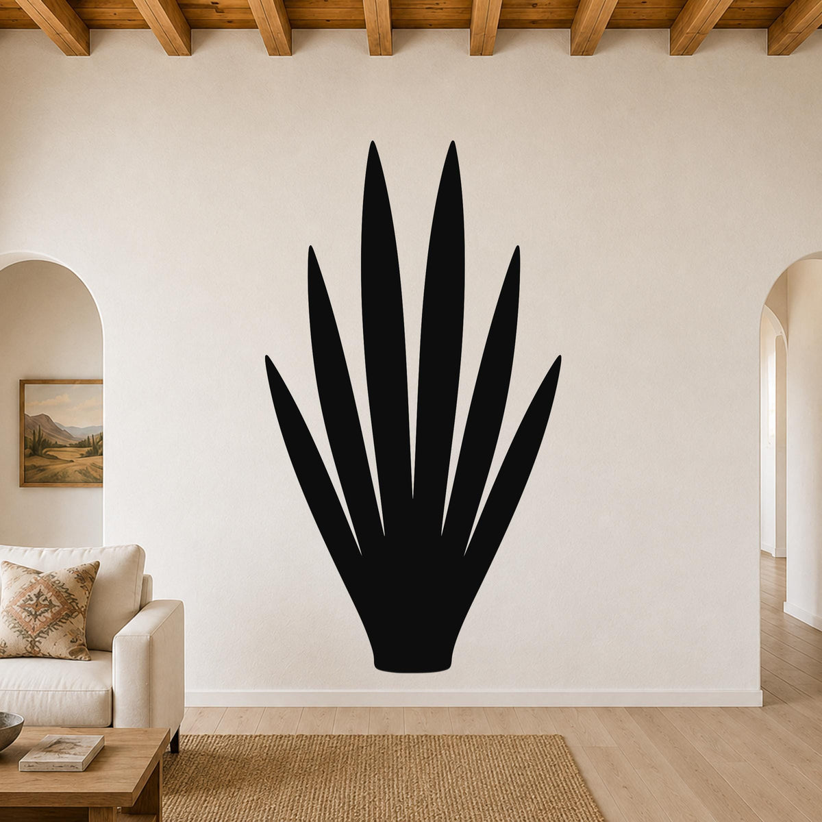 Black metal yucca wall art silhouette with pointed leaves, mounted on a living room wall above a sofa.
