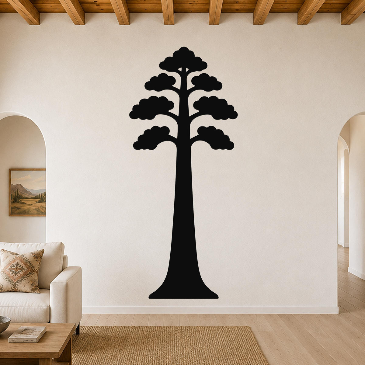 Black metal sequoia tree wall art with layered canopy cutouts, mounted on a living room wall above a sofa.