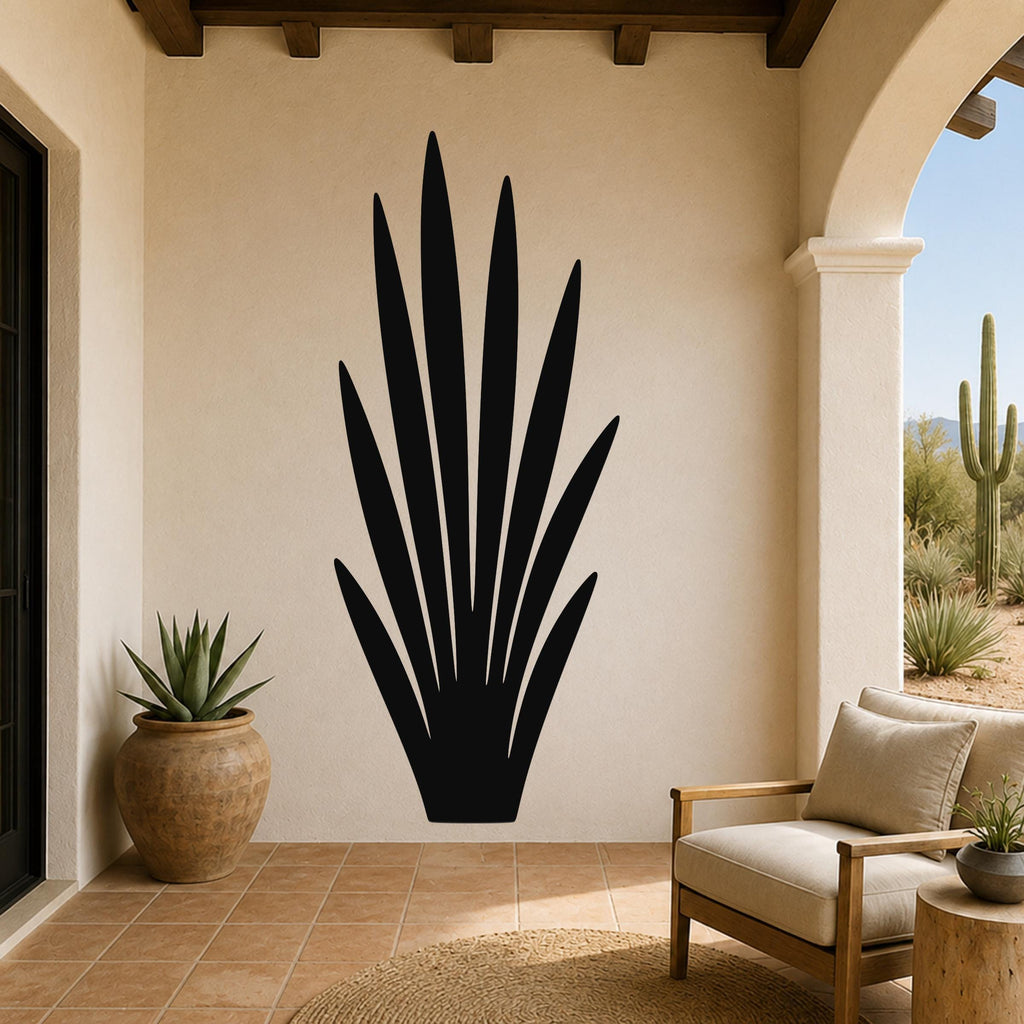 Black metal agave plant wall art with pointed leaf cutouts, mounted on a beige stucco wall in a patio living space.