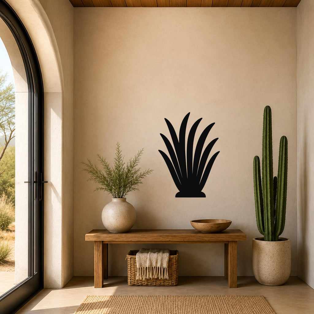 Black metal agave wall art silhouette mounted on a beige wall above a wooden bench in a sunlit entryway.