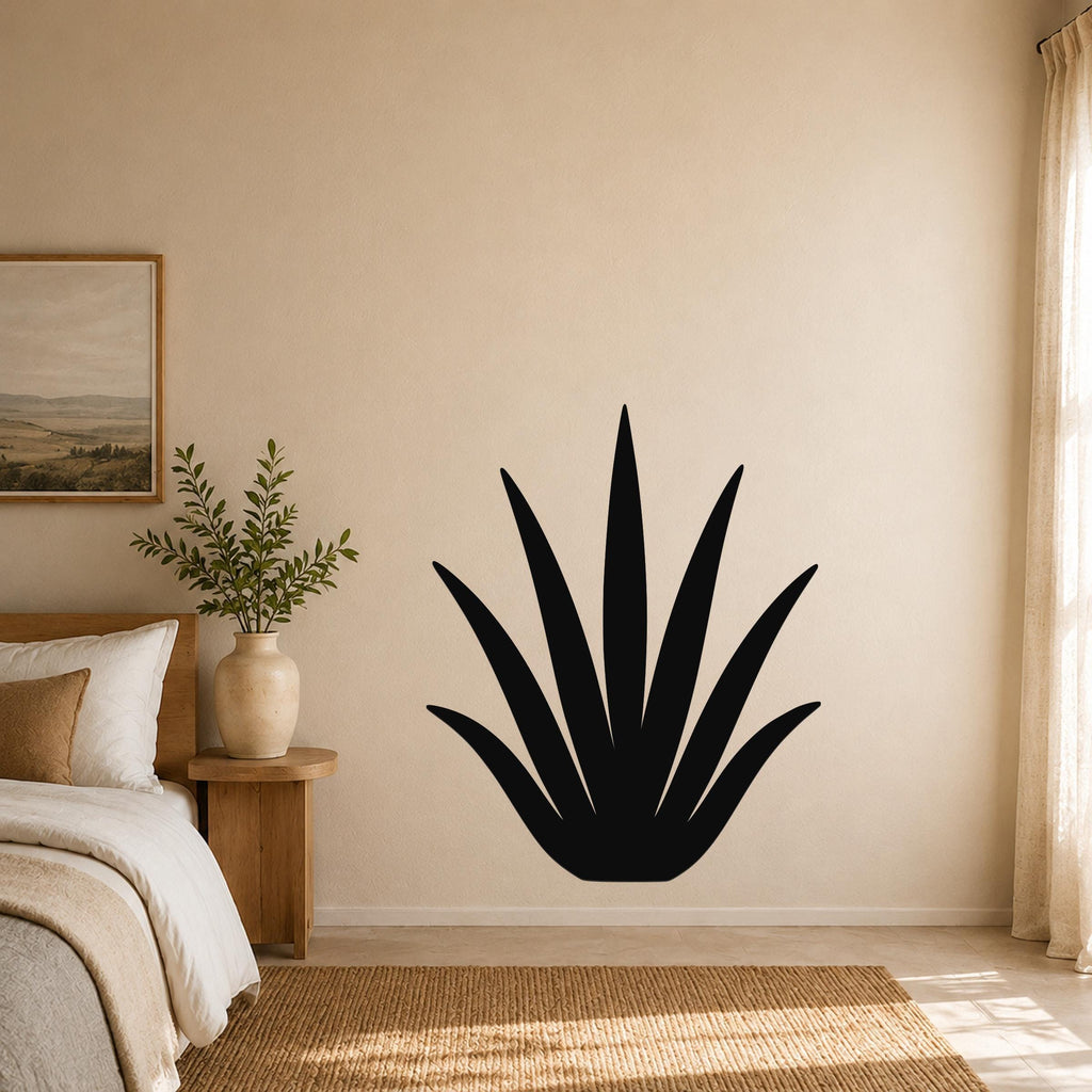 Black metal agave wall art with pointed leaf cutouts, mounted on a beige bedroom wall above a woven rug.