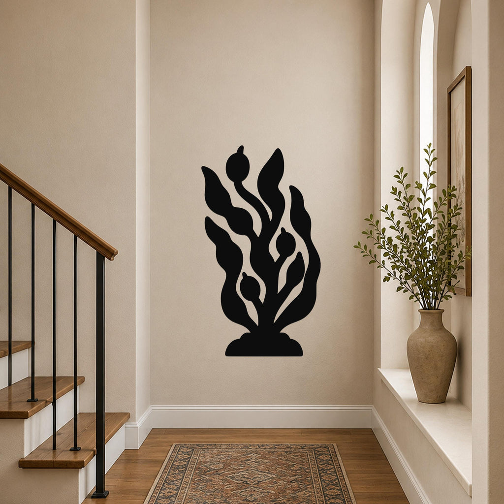 Black metal wall art in a kelp and seaweed silhouette design, mounted on a hallway wall above a patterned rug near a staircase.