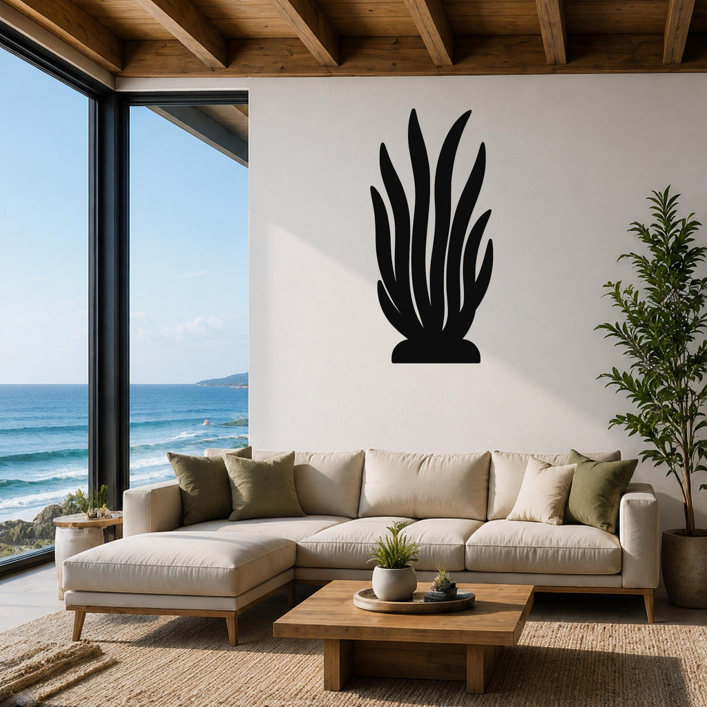 Black metal kelp wall art with tall, flowing leaf cutouts, mounted on a white wall above a beige sectional sofa in a coastal living room.