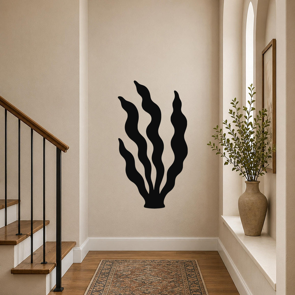 Black metal kelp wall art with wavy blade cutouts, mounted on a hallway wall above a patterned rug near a staircase.