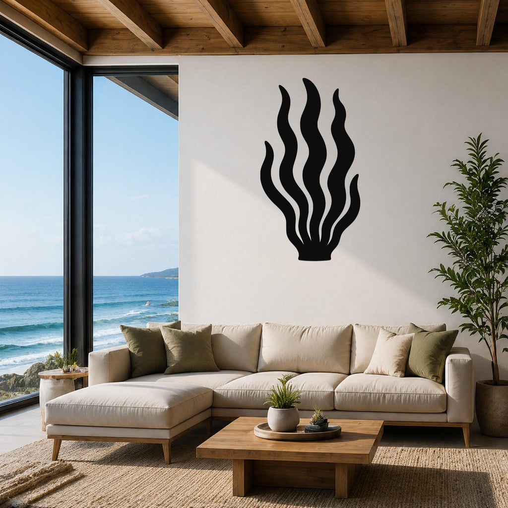 Black metal kelp wall art with flowing frond cutouts, mounted on a white wall above a beige sectional sofa in a coastal living room.