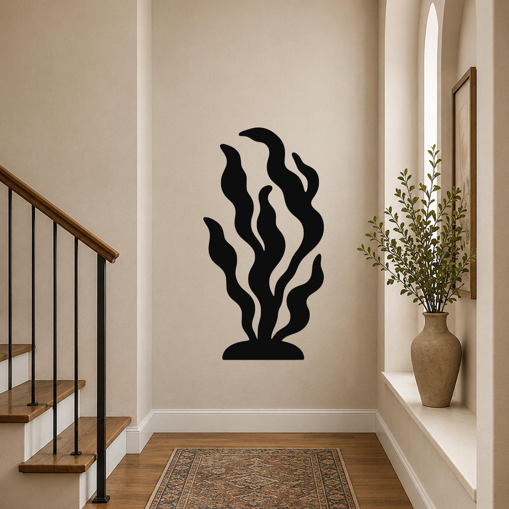 Black metal kelp wall art with flowing leaf cutouts, mounted on a hallway wall above a patterned rug near a staircase.