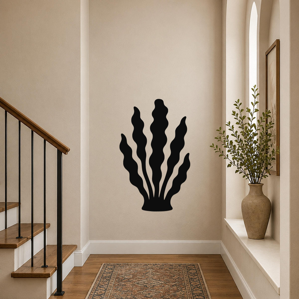 Black metal kelp wall art with wavy leaf cutouts, mounted on a hallway wall above a patterned rug near a staircase.