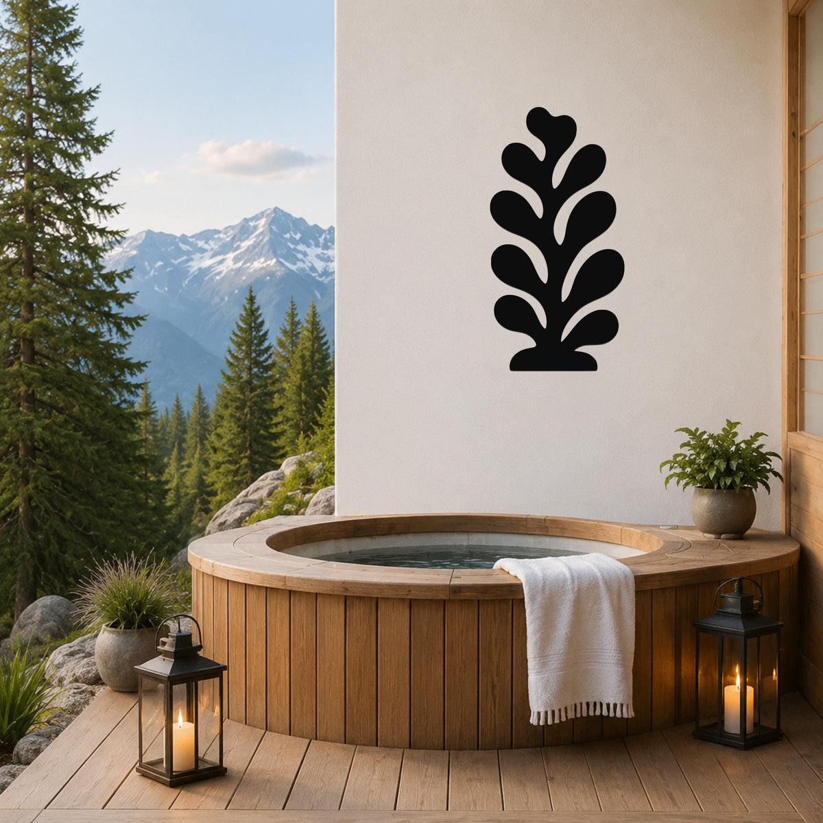 Black metal leaf wall art with layered cutout design, mounted on a white wall above a wooden hot tub on a mountain-view deck.