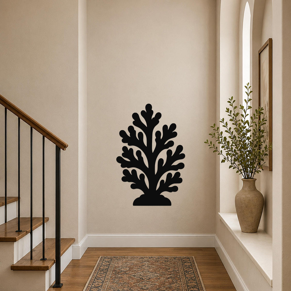 Black metal coral wall art with branching cutouts, mounted on a hallway wall above a patterned rug near a staircase.