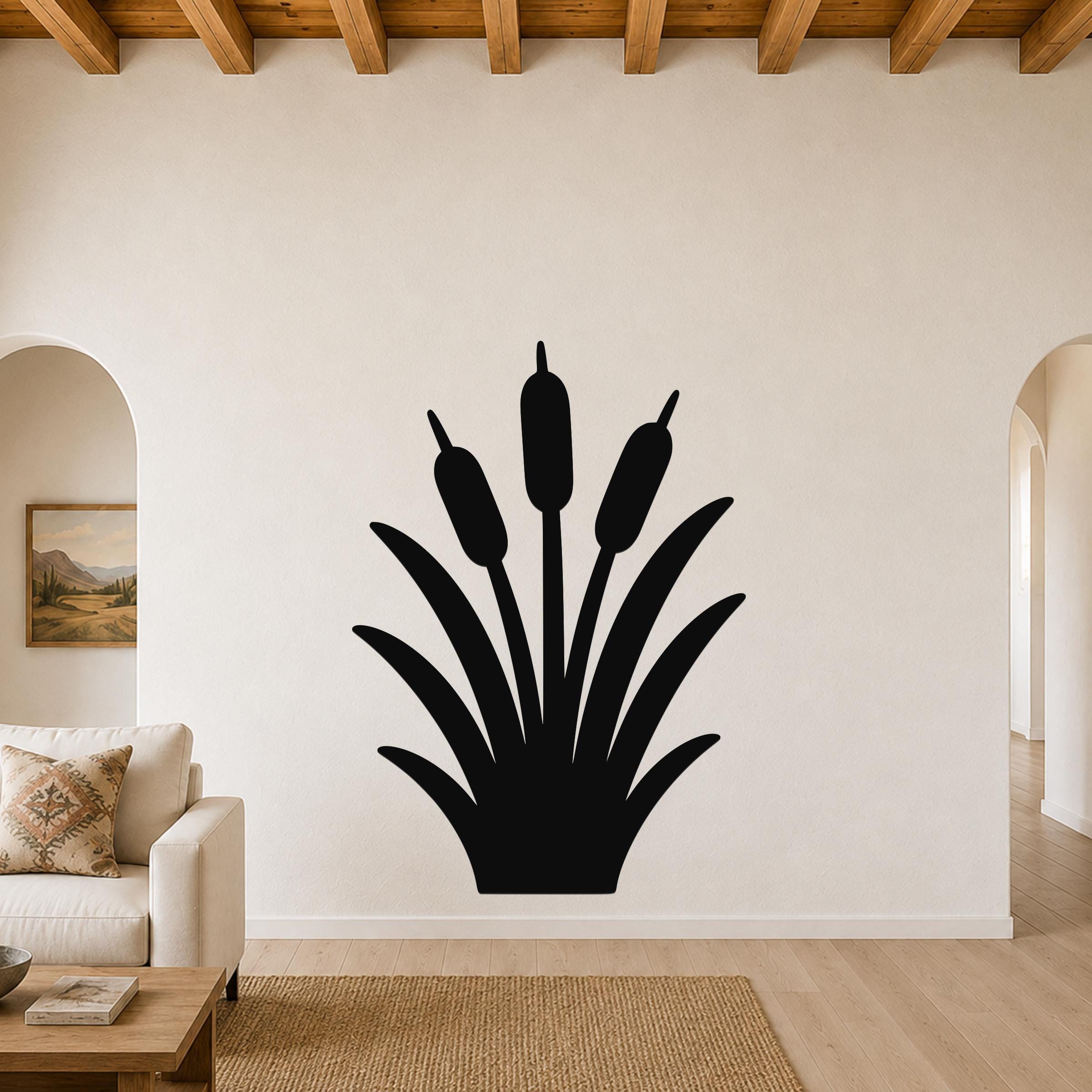 Black metal cattail wall art silhouette with three seed heads, mounted on a living room wall above a sofa.