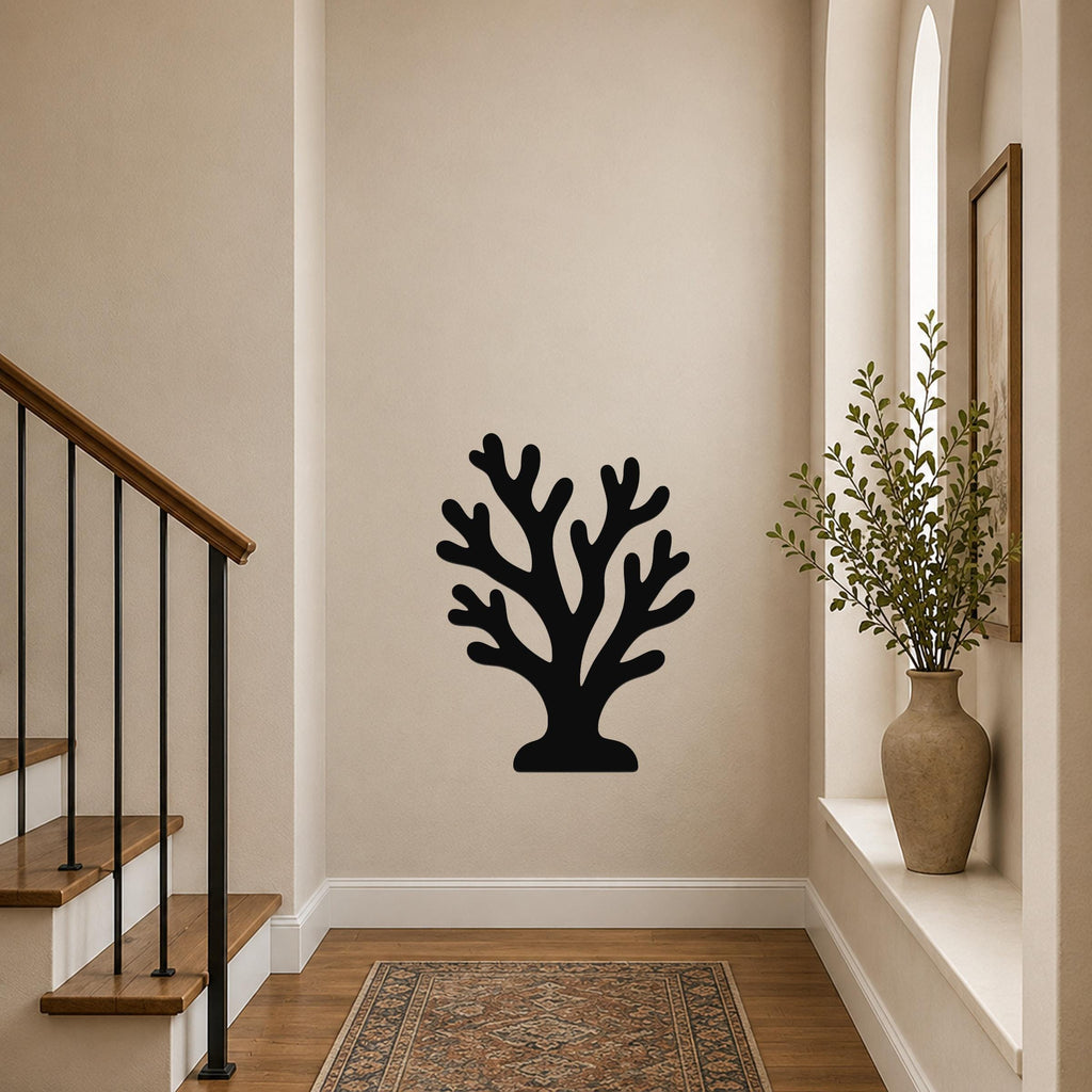 Black metal coral wall art with branching cutouts, mounted on a white siding wall above a poolside planter.