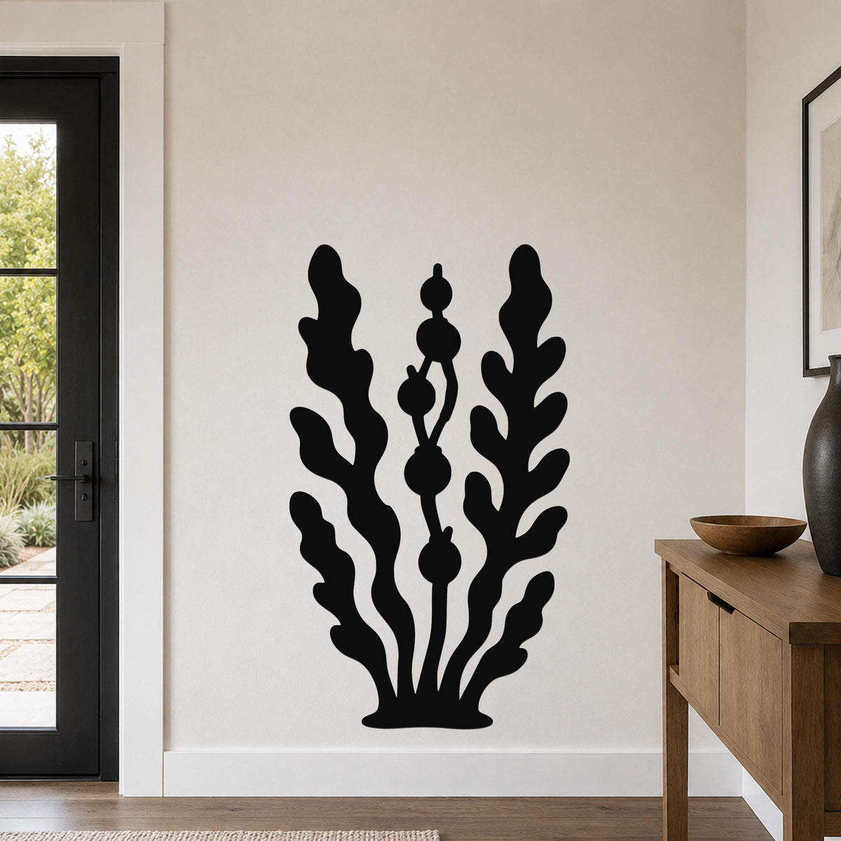 Black metal wall art in a kelp and seaweed silhouette design, mounted on a living room wall above a wooden console table.