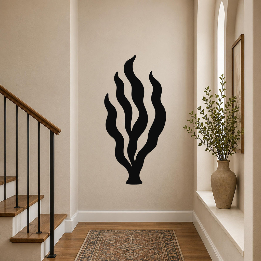 Black metal kelp seaweed wall art with flowing leaf cutouts, mounted on a hallway wall above a patterned rug near a staircase.