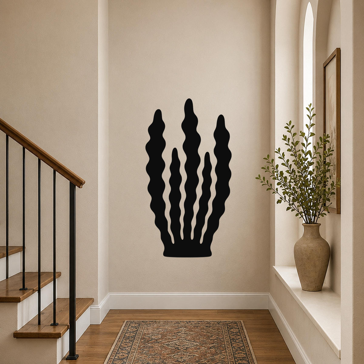 Black metal wall art in a kelp silhouette design with wavy vertical cutouts, mounted on a hallway wall above a patterned rug.