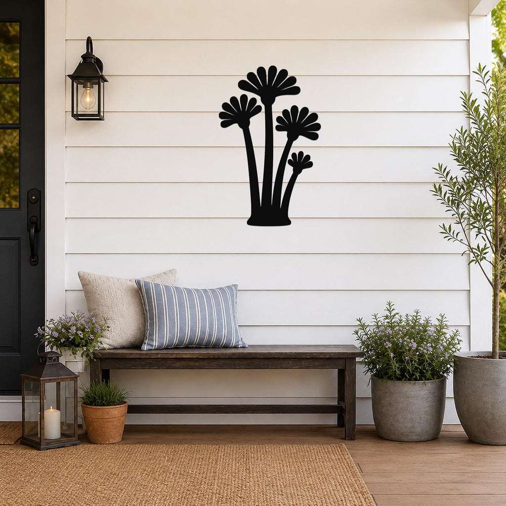Black metal wall art featuring a silhouette of three fan palm trees, mounted on a white shiplap wall above a wooden bench on a porch.