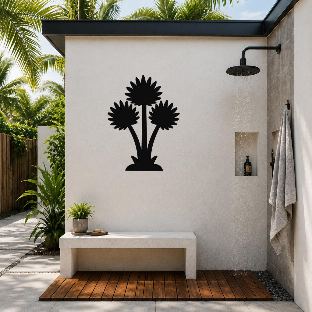 Black metal wall art with a silhouette of three wildflowers, mounted on a white outdoor shower wall above a concrete bench.