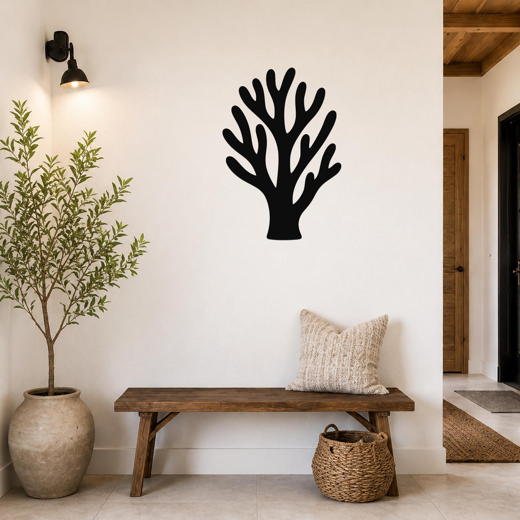 Black metal coral wall art with branching cutouts, mounted on a white wall above a wooden bench in a hallway entryway.