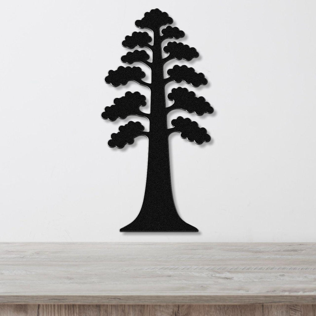 Black metal wall art in the silhouette of a sequoia tree with layered branch cutouts, mounted on a white wall above a light wood surface.
