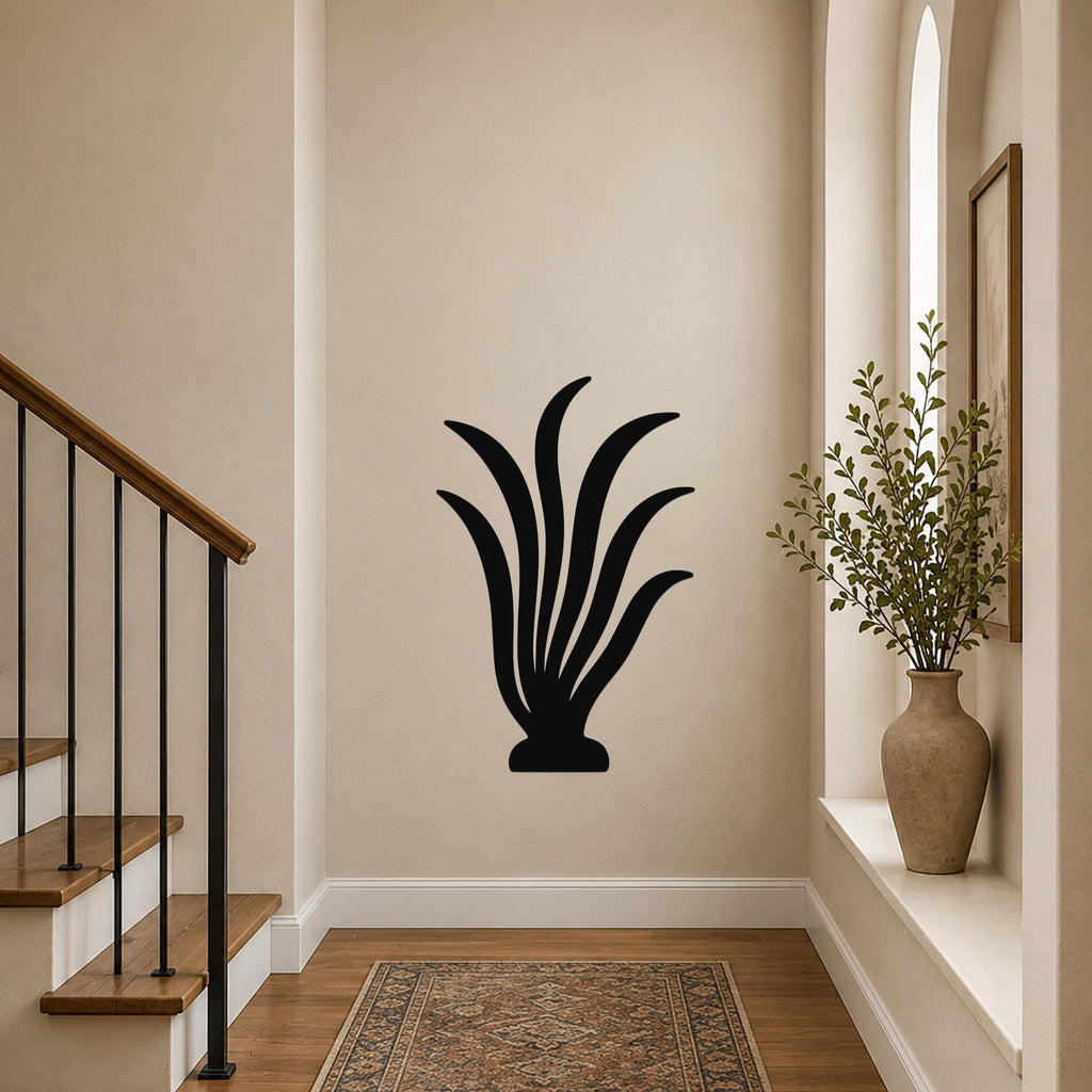 Black metal wall art in a kelp or seaweed silhouette design, mounted on a hallway wall above a patterned rug near a staircase.