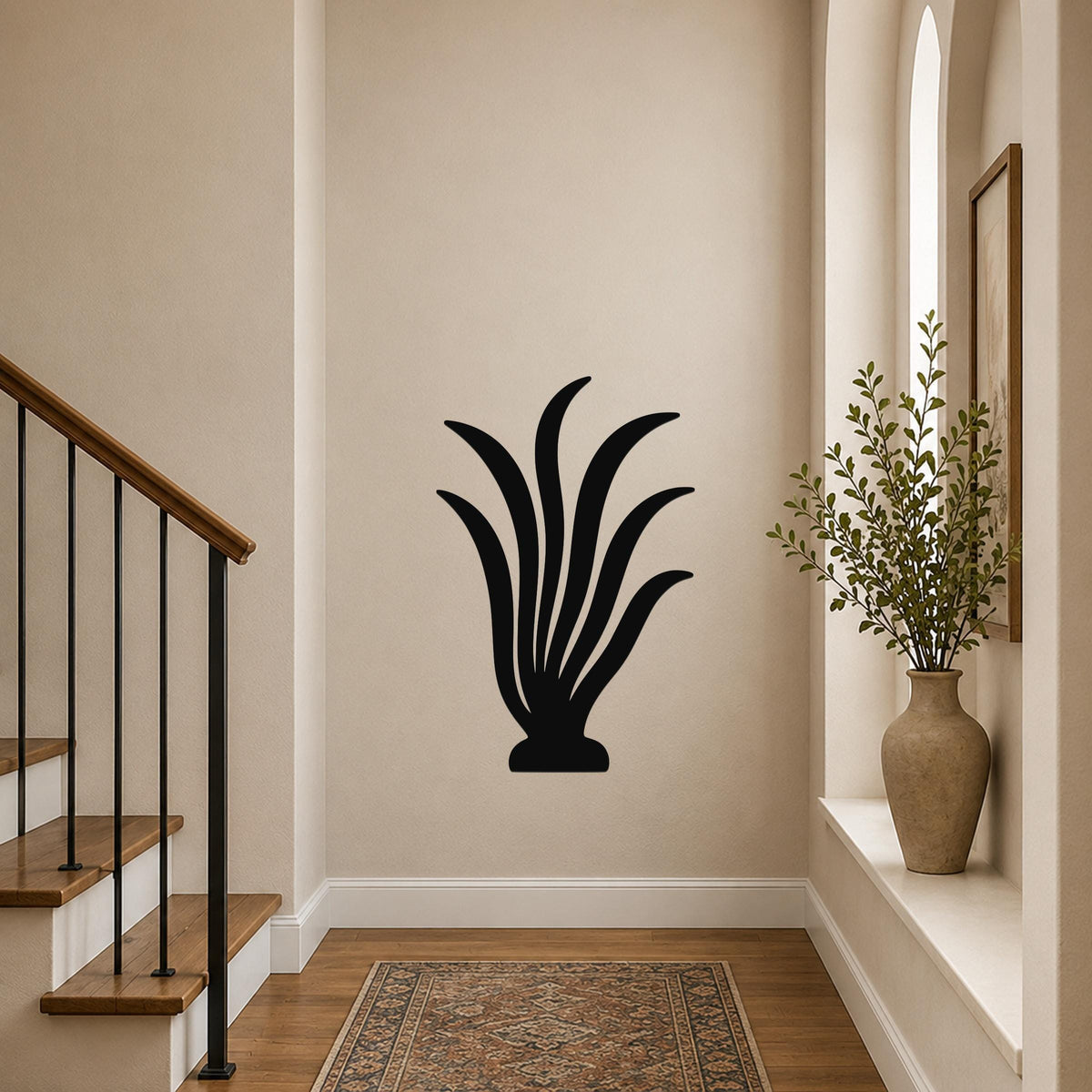 Black metal wall art in a kelp or seaweed silhouette design, mounted on a hallway wall above a patterned rug near a staircase.