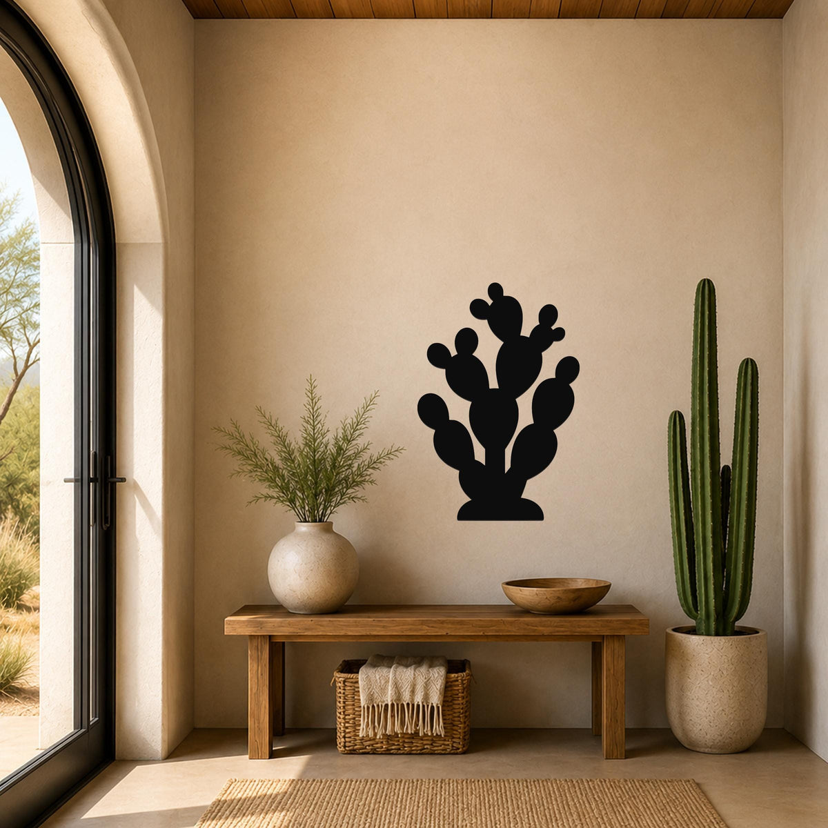 Black metal prickly pear cactus wall art with multiple rounded pads and cutout details, mounted on a beige wall above a wooden bench in a sunlit entryway.