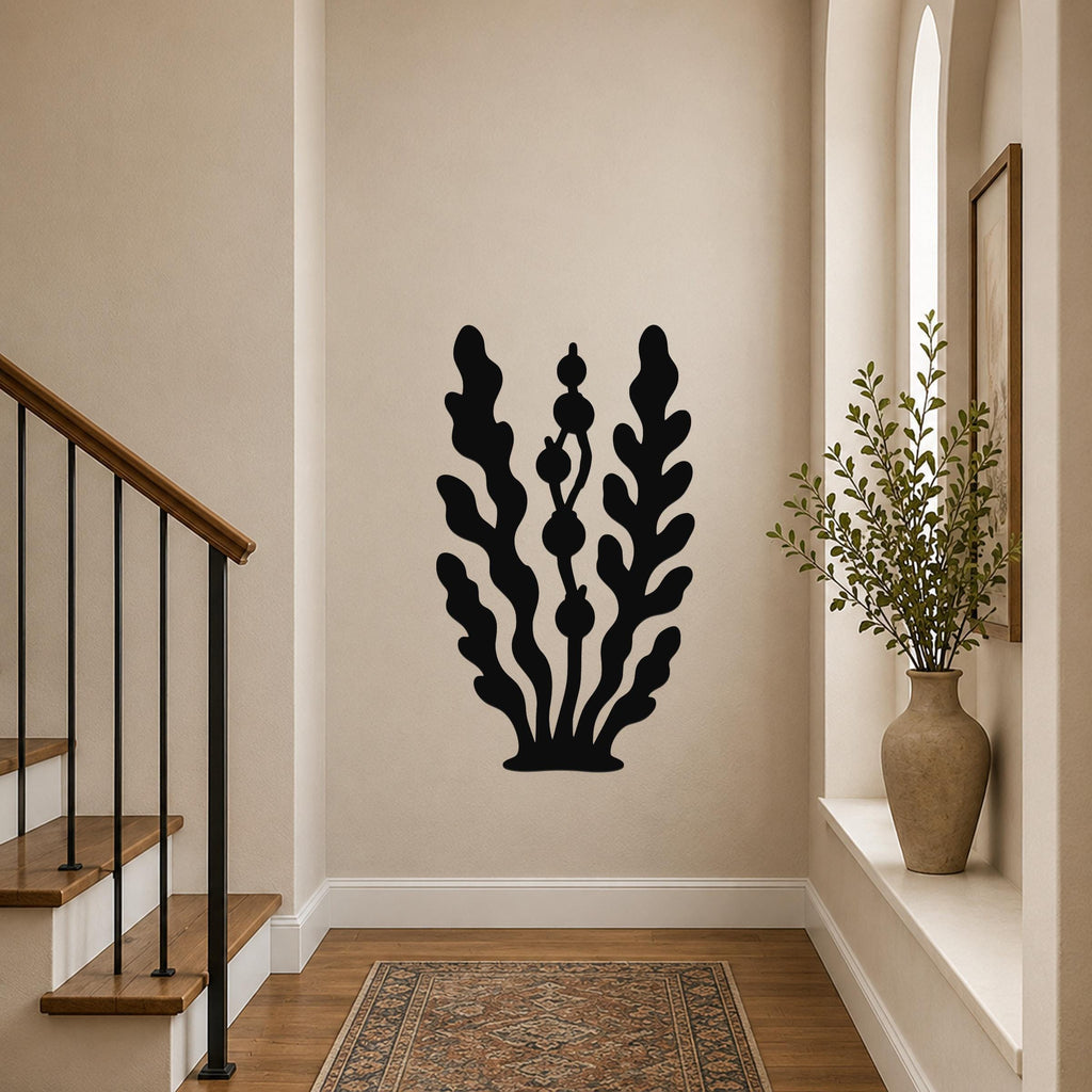 Black metal wall art in a kelp and seaweed silhouette design, mounted on a hallway wall above a patterned rug near a staircase.