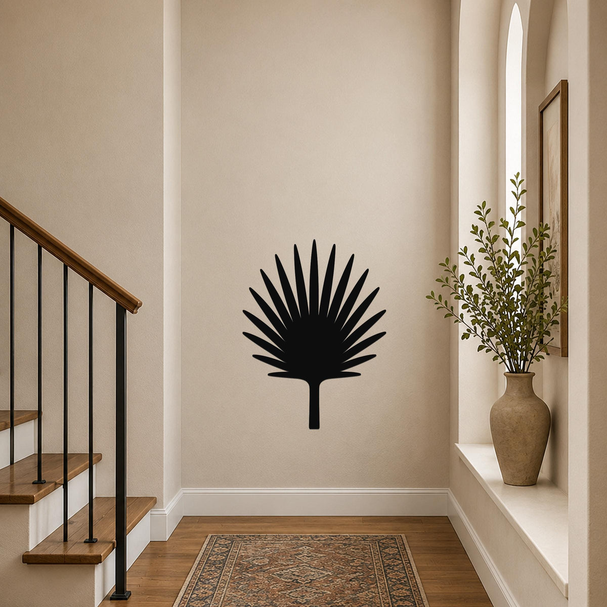 Black metal fan palm tree wall art with radiating leaf cutouts, mounted on a hallway wall above a patterned rug near a staircase.