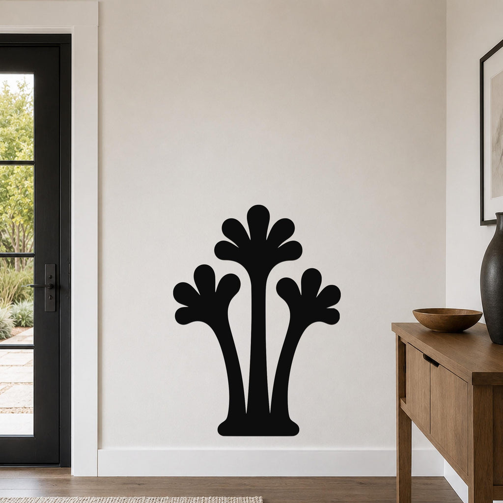 Black metal wall art in a silhouette of three abstract palm trees, mounted on a light-colored wall in a modern entryway.