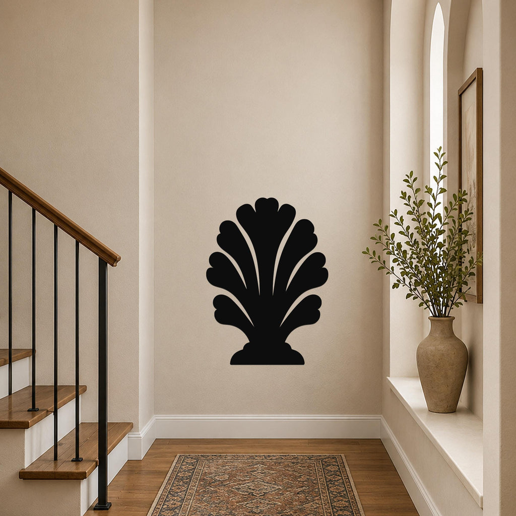 Black metal wall art in a scallop shell silhouette, mounted on a hallway wall above a patterned rug near a staircase.