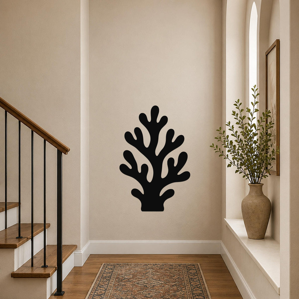 Black metal coral wall art with branching cutouts, mounted on a hallway wall above a patterned rug near a staircase.