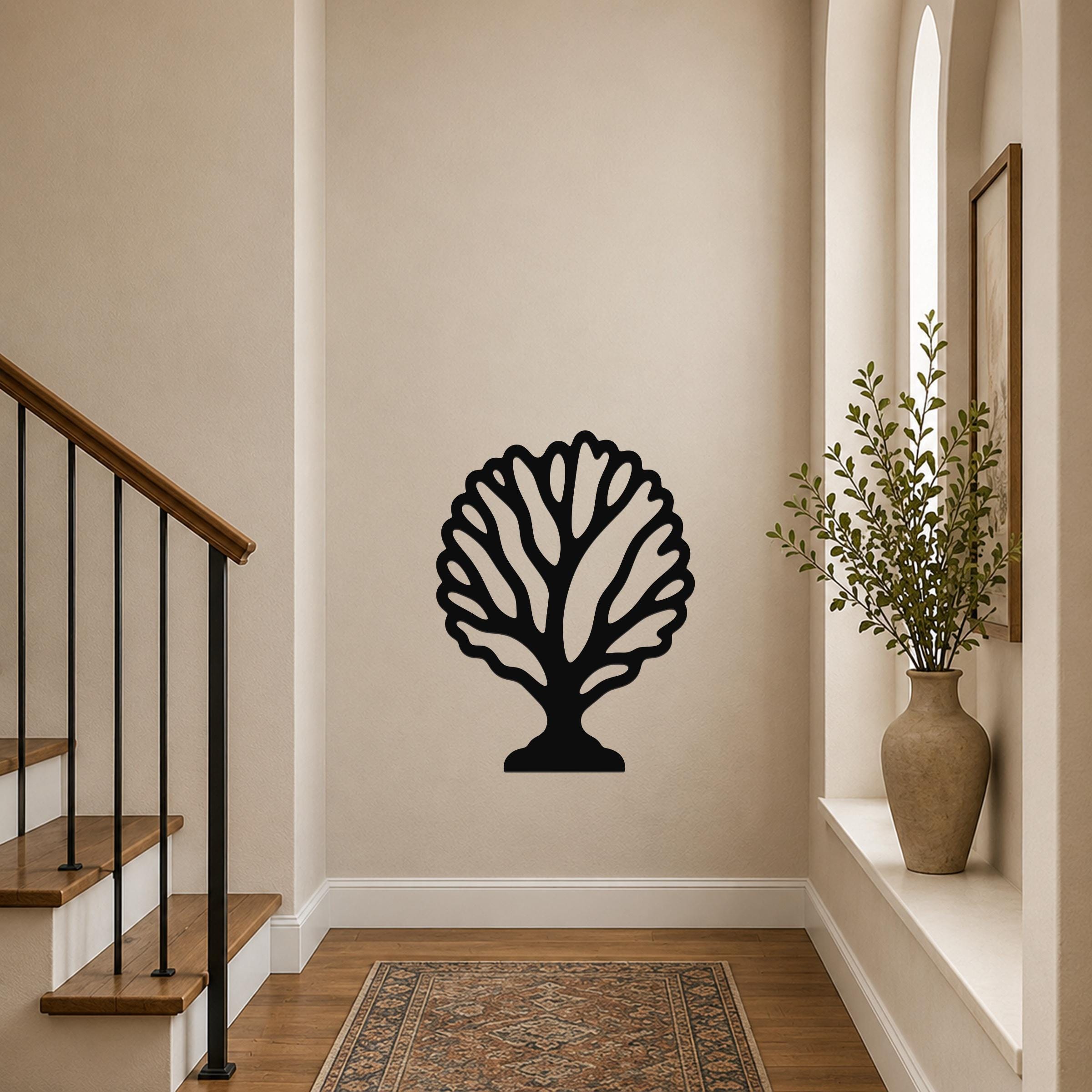 Black metal fan coral wall art with intricate branch cutouts, mounted on a hallway wall above a patterned rug near a staircase.