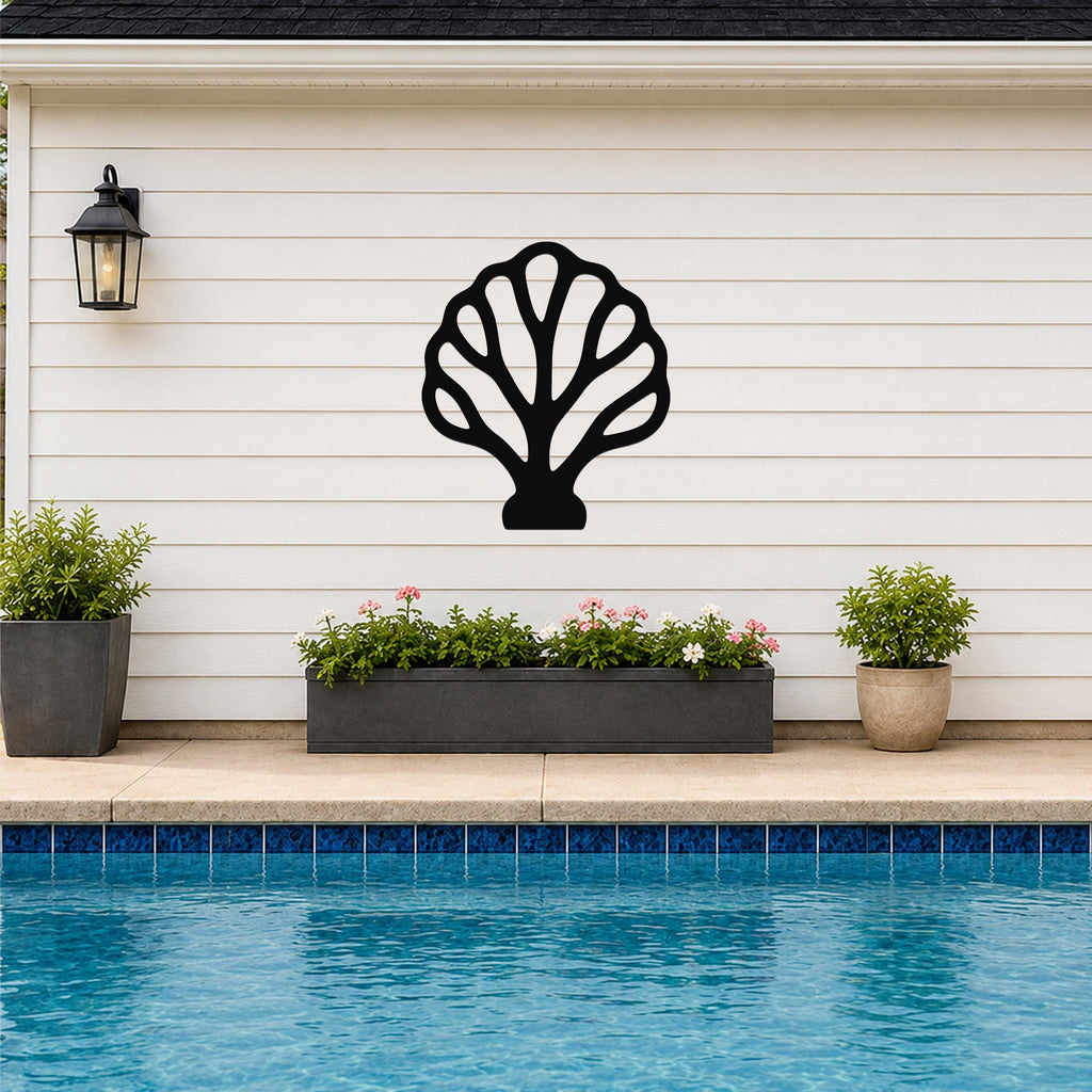 Black metal fan coral wall art with open internal cutouts, mounted on a white horizontal siding wall above a poolside planter.