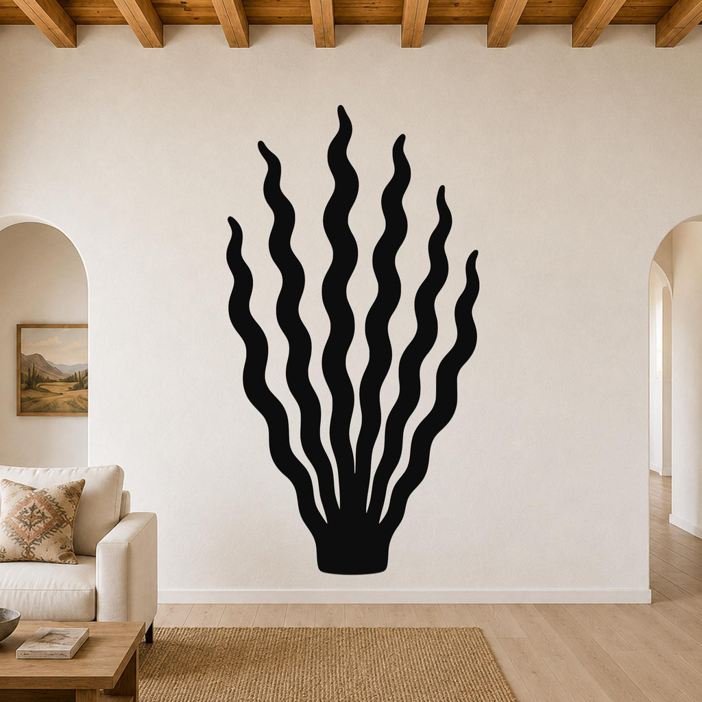 Black metal wall art in a kelp or seaweed silhouette with wavy fronds, mounted on a living room wall above a sofa.