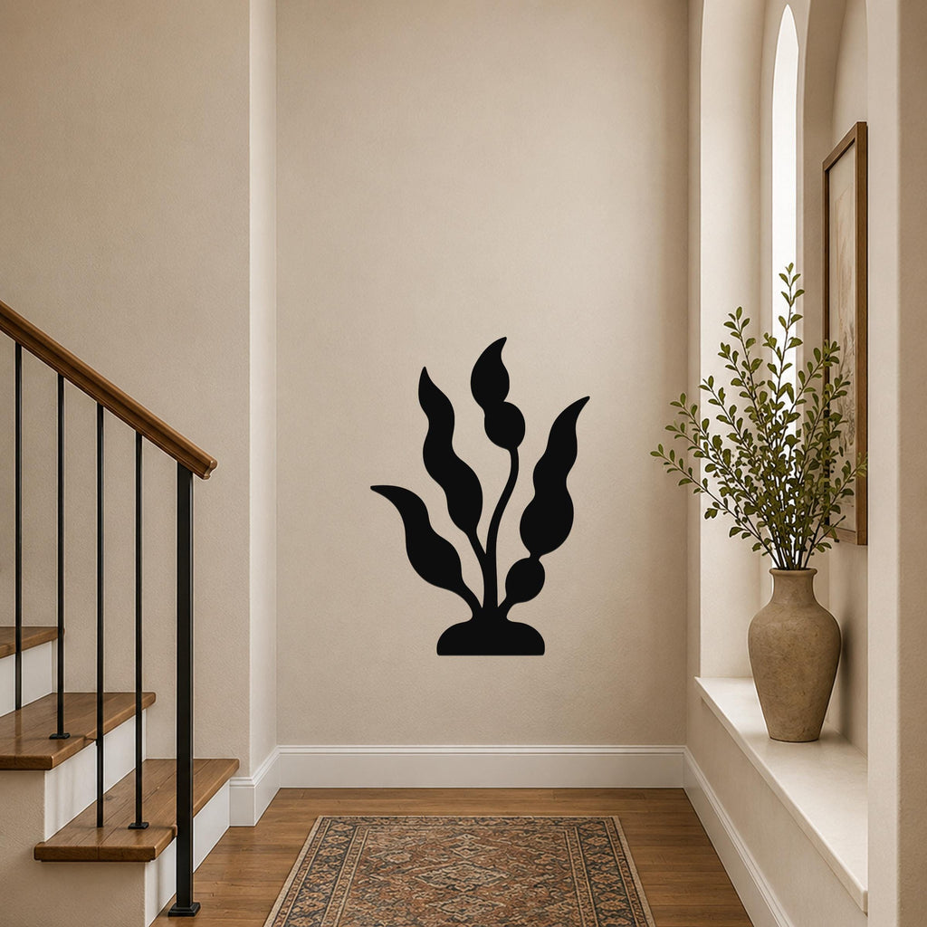Black metal wall art in a kelp or seaweed silhouette, mounted on a hallway wall above a patterned rug near a staircase and window.