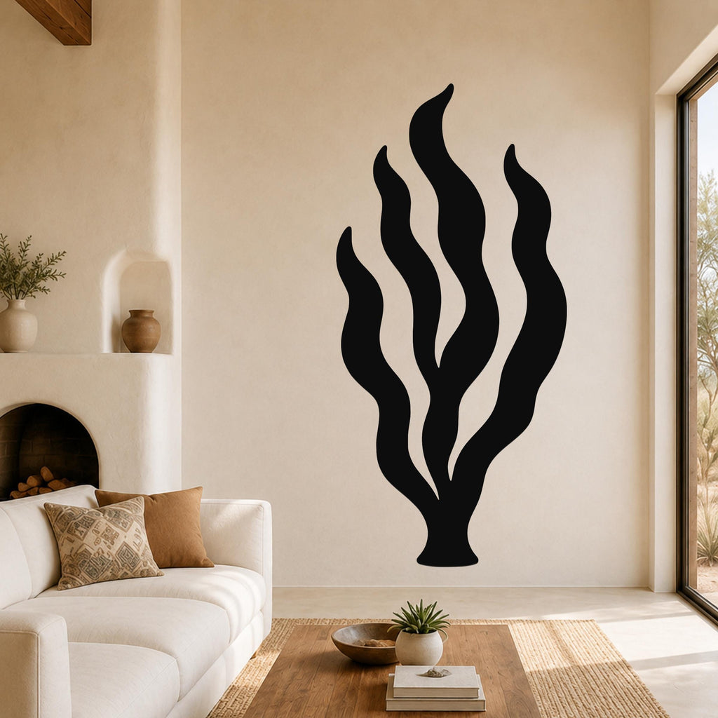 Black metal kelp seaweed wall art with flowing frond cutouts, mounted on a living room wall above a sofa.