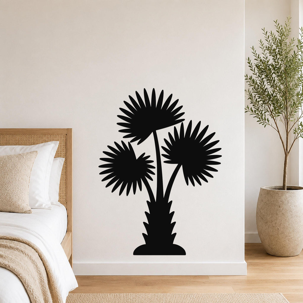 Black metal wall art silhouette of a California fan palm tree with three fronds, mounted on a bedroom wall above a bed.