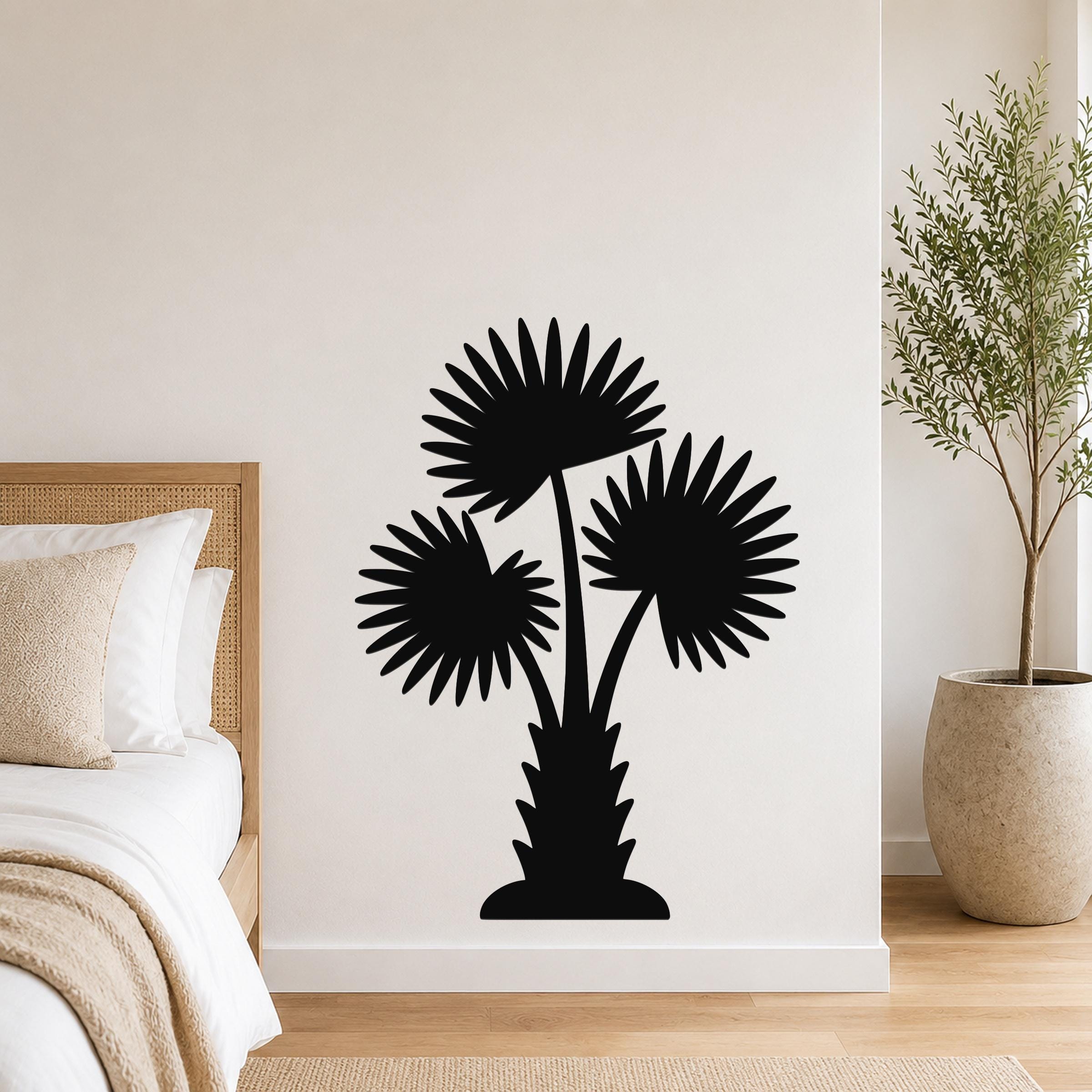 Black metal wall art silhouette of a California fan palm tree with three fronds, mounted on a bedroom wall above a bed.