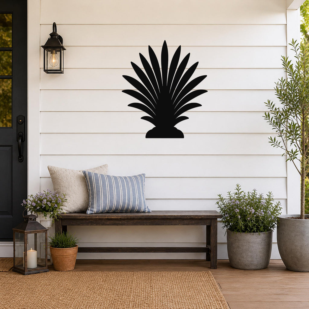 Black metal palm tree wall art with fan-shaped fronds, mounted on a white shiplap wall above a wooden bench on a porch.