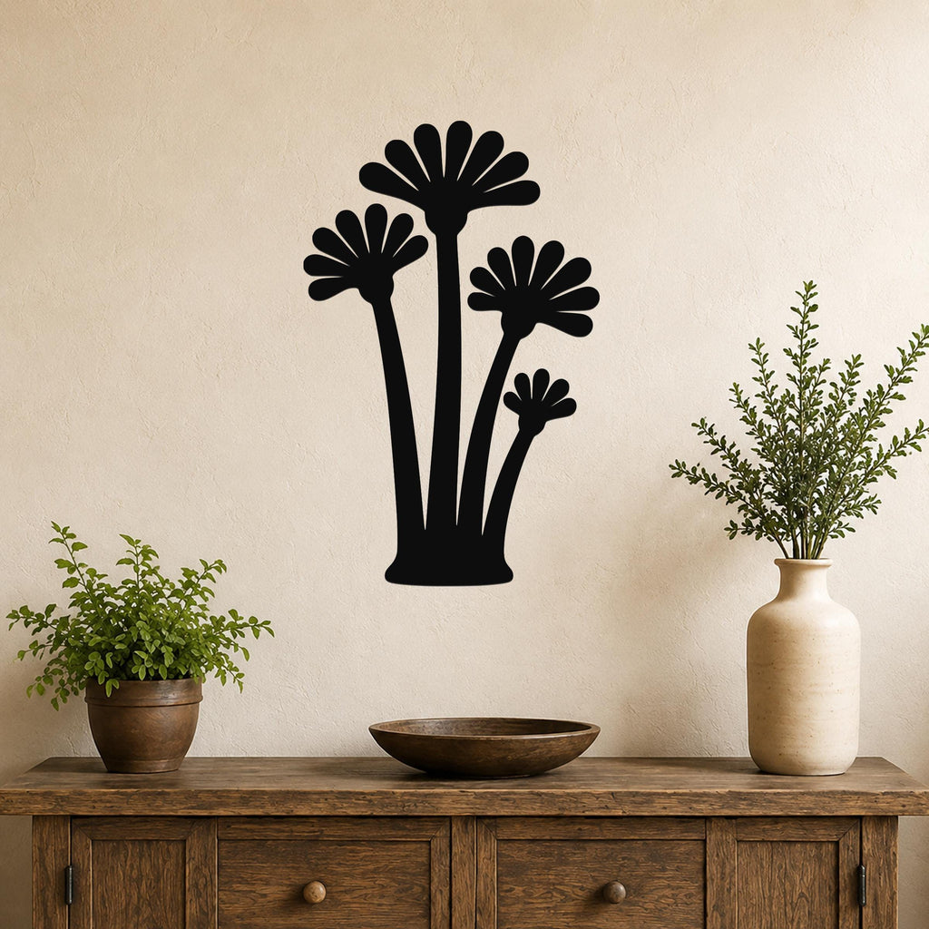 Black metal wall art with a fan palm tree silhouette, mounted on a beige wall above a wooden console table with potted plants.