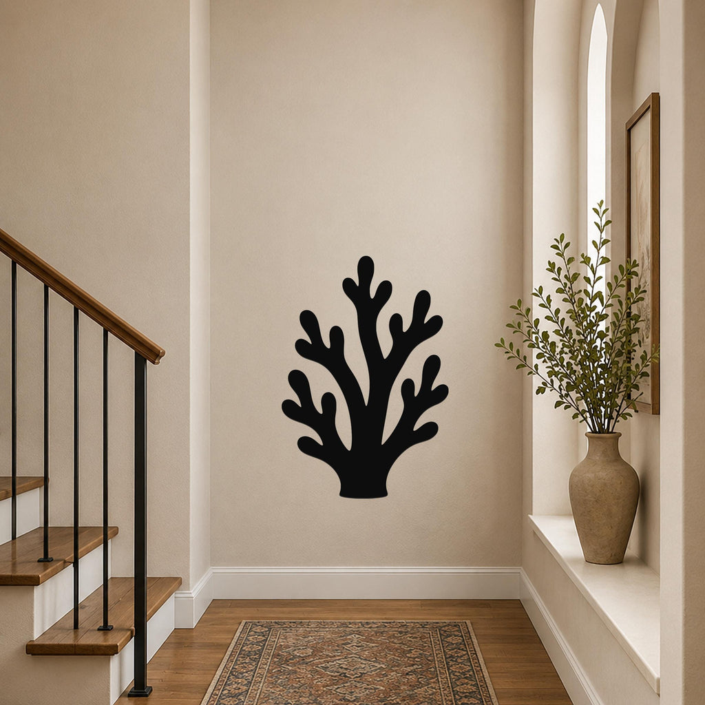 Black metal branching coral wall art with cutout details, mounted on a hallway wall above a patterned rug near a staircase.