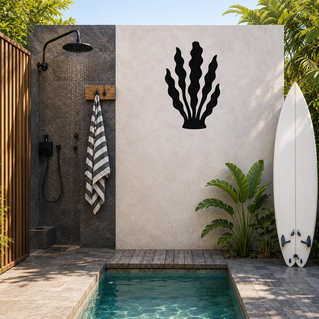 Black metal kelp wall art with wavy leaf cutouts, mounted on a light-colored outdoor wall beside a shower and pool area.