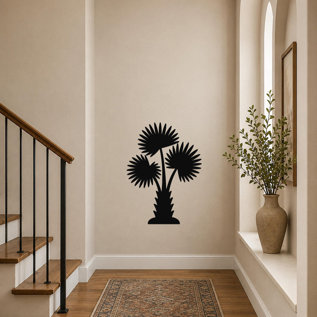 Black metal wall art silhouette of a California fan palm tree with three fronds, mounted on a hallway wall near a staircase and a vase with greenery.